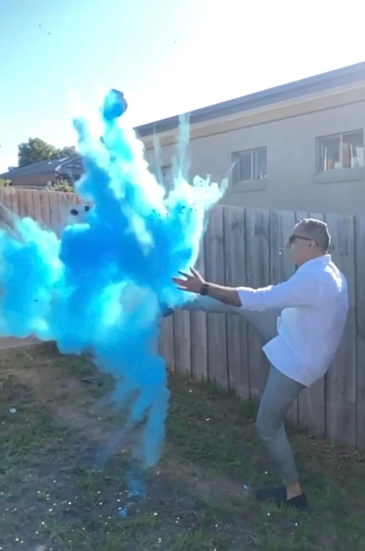 "Customer kicking blue powder-filled gender reveal soccer ball during outdoor football-themed baby reveal.